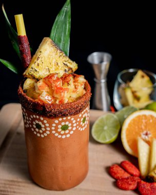 Lezzetli Meksika karışımı biberli ananas ve arka planda taze malzemeler bulunan kil bardakta tekila..