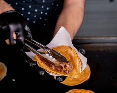 Guadalajara stili birria taco hazırlayan kişi tortilla, soğan ve kişniş.