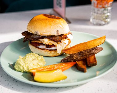 Patates kızartması ve bir porsiyon guacamole ile servis edilen yumurta ve domuz pastırması ile nefis dilimler..