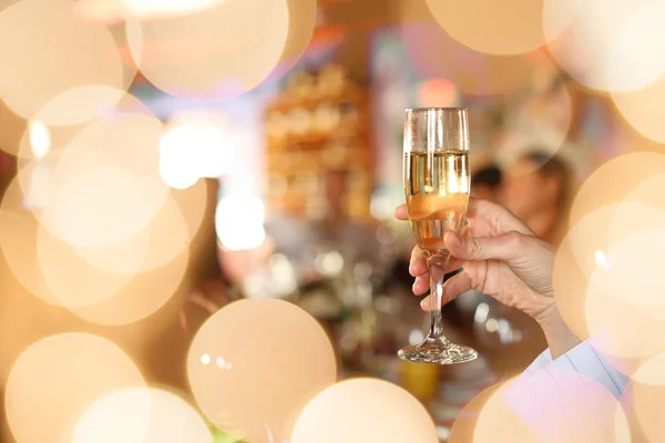 Hand som håller glas champagne på fest — Stockfoto