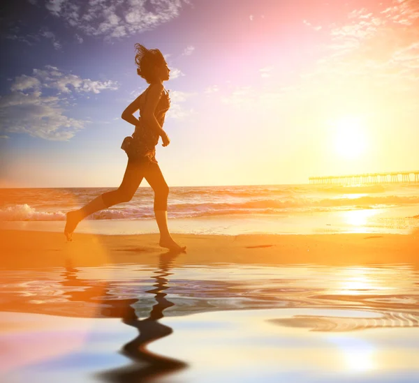 Женщина, бегущая по океану на закате — стоковое фото