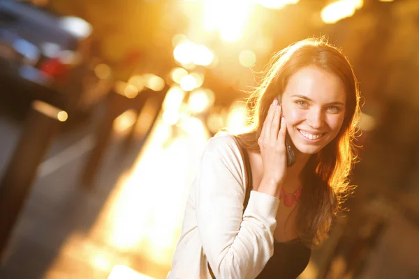 Mujer sonriendo y hablando por teléfono celular en la calle —  Fotos de Stock