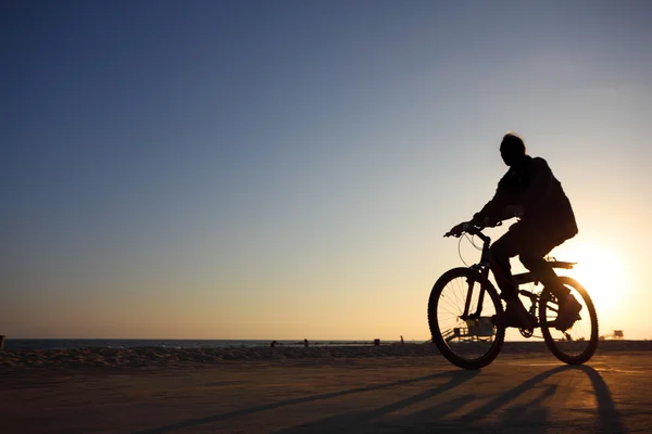 Biker silueta de echitatie de-a lungul plajei la apus de soare — Fotografie, imagine de stoc