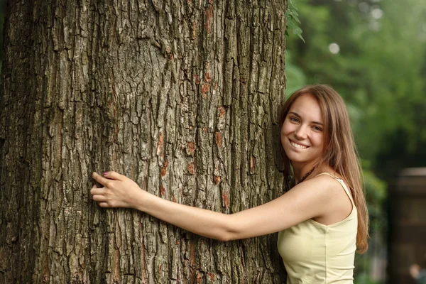 Happy beautiful girl hugging big tree in park — Stock Photo, Image