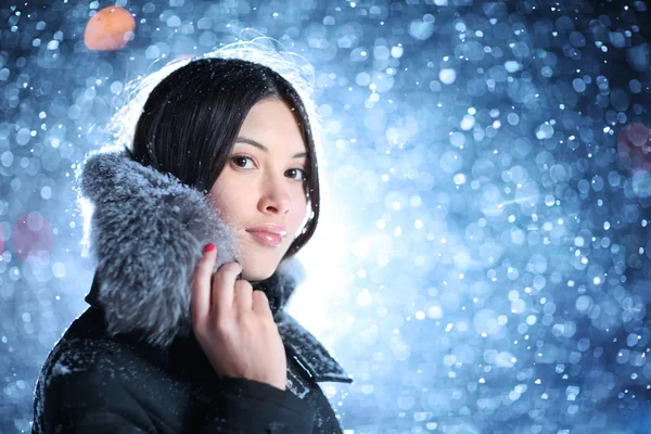 Jonge vrouw op vallende sneeuw achtergrond — Stockfoto