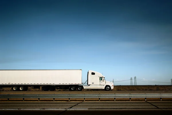 Witte vrachtwagen op de weg onder de blauwe hemel — Stockfoto