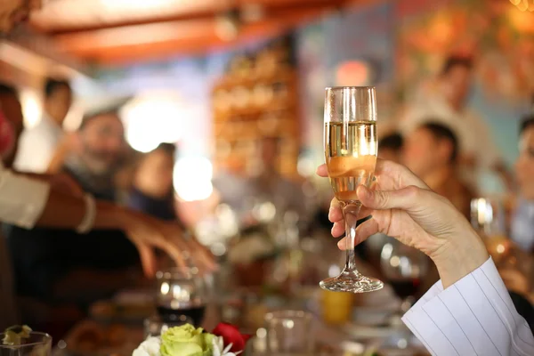 Hand holding glass of champagne at party — Stock Photo, Image