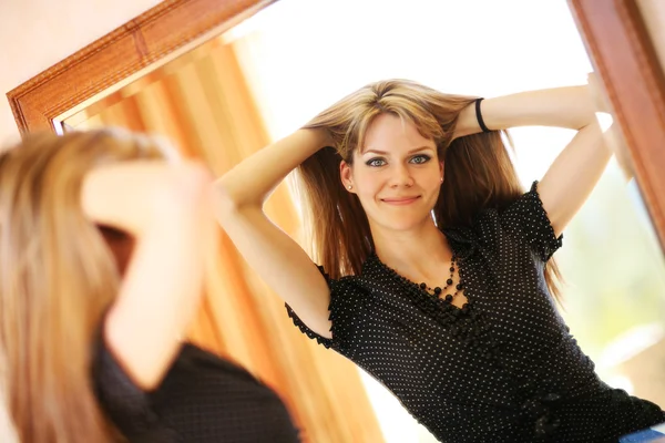 Beautiful young woman looking in the mirror — Stock Photo, Image