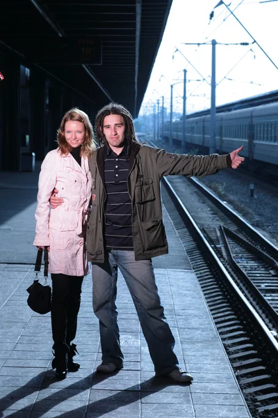 Young couple hitchhiking at train station — Stock Photo, Image