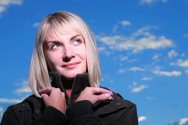 Prachtige blond meisje over blauwe hemel bij zonsondergang — Stockfoto