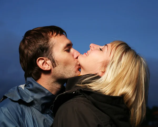 Young couple kissing outdoors at dusk. — Stock Photo, Image