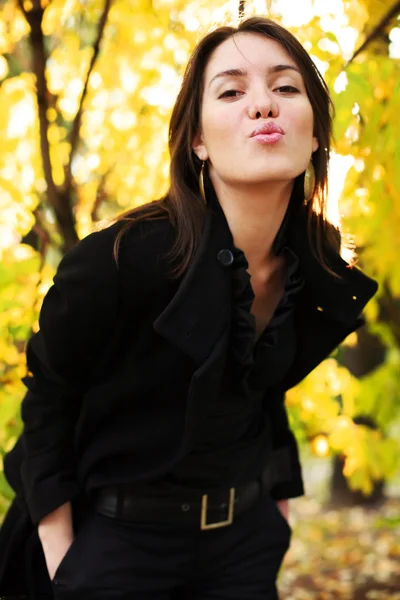 Donna soffiando un bacio in giallo autunno foresta — Foto Stock