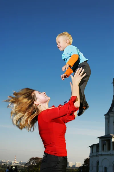 Young mother lifting small son in the sky. — Stock Photo, Image