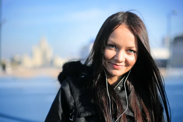 Дівчина посміхається і слухає портативну музику в зимовому місті — стокове фото