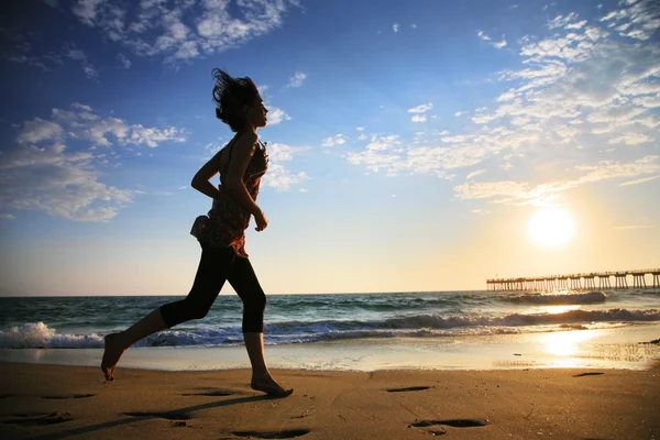 Girl running by the ocean at sunset — Stock Photo, Image