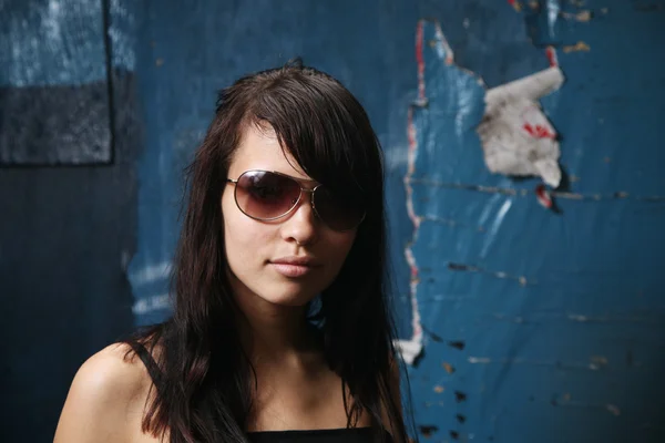 Девушка в солнечных очках на фоне огромной стены — стоковое фото