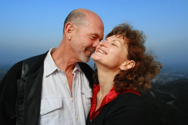 Happy mature couple embracing ontop of a city. — Stock Photo, Image