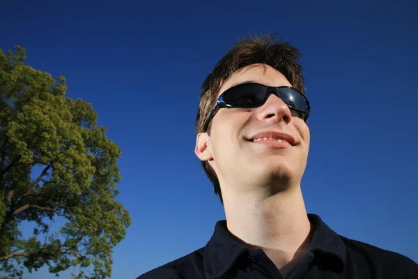 Jeune homme souriant avec des lunettes de soleil — Photo