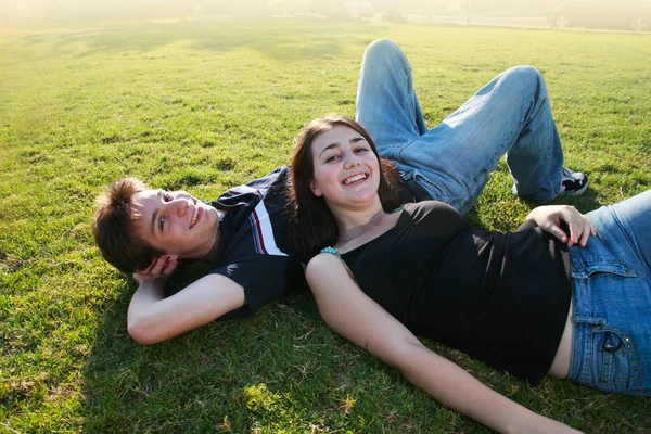 Счастливая молодая пара лежит на зеленом поле — стоковое фото