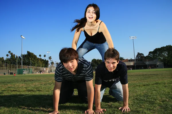 Trois amis faisant pyramide sur un stade — Photo