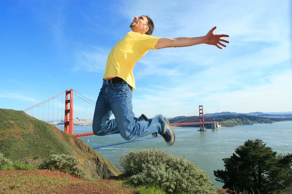 Mann springt neben der goldenen Torbrücke — Stockfoto