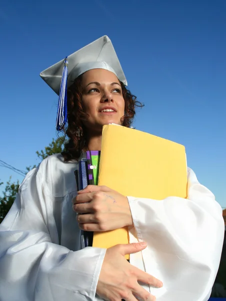 Étudiant diplômé tenant une grande pile de manuels scolaires — Photo