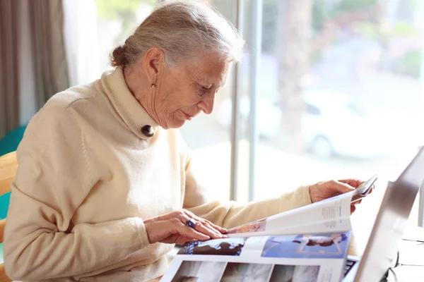 Äldre dam läsande magazine. — Stockfoto