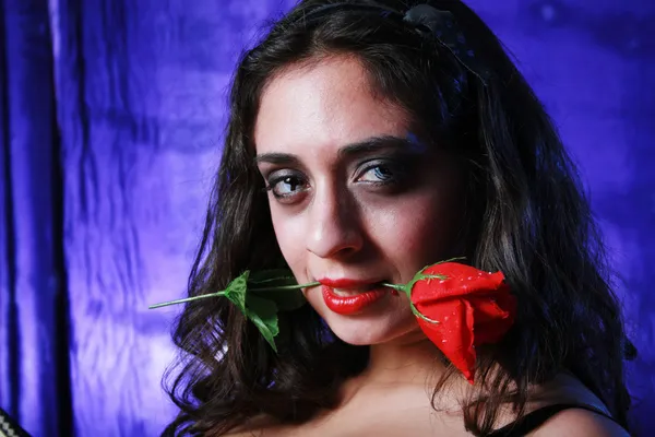 Brunette met rode roos in haar mond — Stockfoto