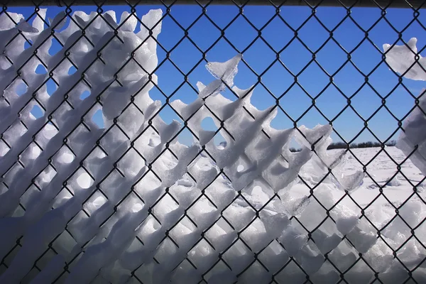 Snowy fence, blue sky behind. — Stock Photo, Image