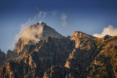 Gün batımında bulutlarla gözlemevi ile Lomnicky dik zirvesi