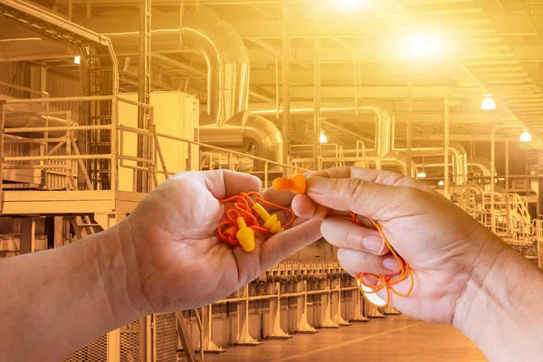 Ear plugs hearing protection in men's hand on factory worker background,safety concep