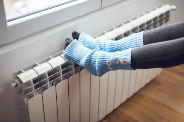 Yünlü çoraplı bir kadın, radyatörde eğleniyor..