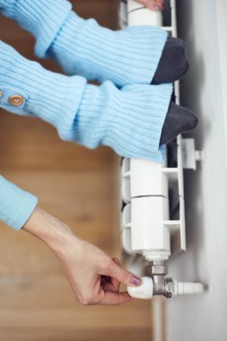 Yünlü çoraplı bir kadın, radyatörde eğleniyor..