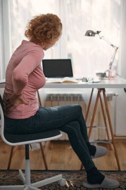Kalçası, sırtı, omurga spazmı, kramp ve ağrısı olan, ev sorunları ve sorunları ile çalışan bir kadın..