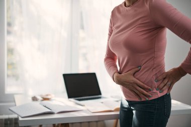 Kalçası, sırtı, omurga spazmı, kramp ve ağrısı olan, ev sorunları ve sorunları ile çalışan bir kadın..