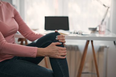 Kasılma, kramp, burkulma, çıkık diz ve eklem ağrısı olan bir kadın, ev sorunları ve sorunları ile çalışıyor..