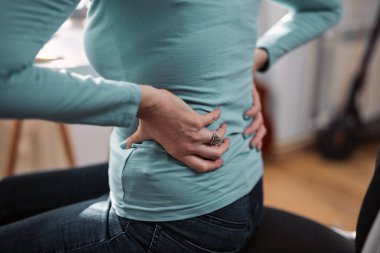 Kalçası, sırtı, omurga spazmı, kramp ve ağrısı olan, ev sorunları ve sorunları ile çalışan bir kadın..