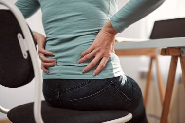 Kalçası, sırtı, omurga spazmı, kramp ve ağrısı olan, ev sorunları ve sorunları ile çalışan bir kadın..