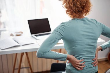 Kalçası, sırtı, omurga spazmı, kramp ve ağrısı olan, ev sorunları ve sorunları ile çalışan bir kadın..