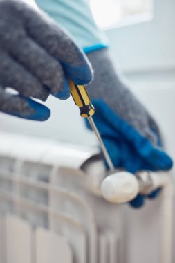 Eldivenleri tamir eden ve evdeki merkezi ısıtma gaz radyatöründen kanayan havayı tamir eden tamirci..