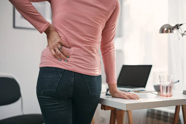 Woman with hip, back, spine spasm, cramp and pain, working from home troubles and issues.