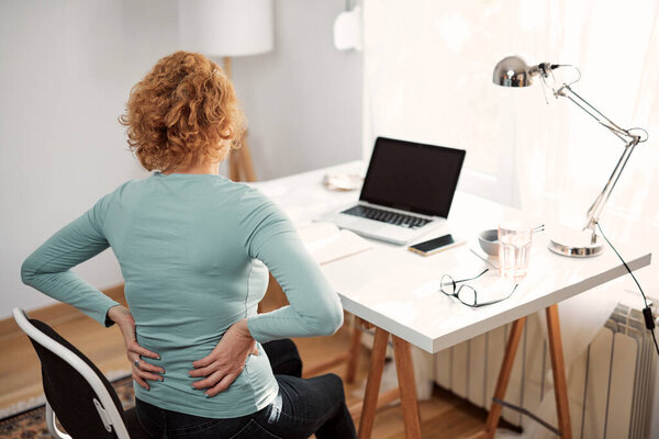 Woman with hip, back, spine spasm, cramp and pain, working from home troubles and issues.