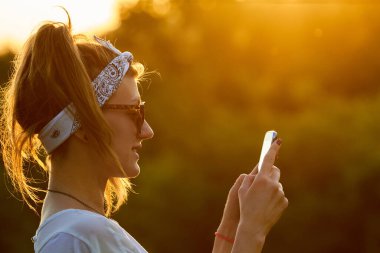 Modern akıllı telefonu açık havada kullanan bir kadın..