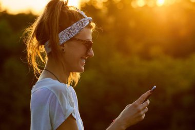 Modern akıllı telefonu açık havada kullanan bir kadın..