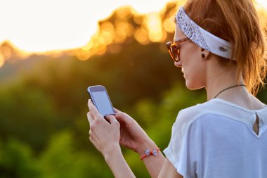 Modern akıllı telefonu açık havada kullanan bir kadın..
