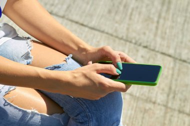 Modern akıllı telefonu açık havada kullanan bir kadın..