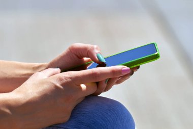 Modern akıllı telefonu açık havada kullanan bir kadın..