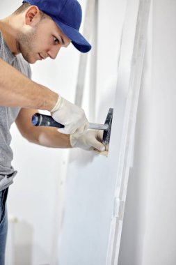 Genç, yetişkin bir adam yeni evini boyayıp tamir ediyor..