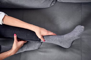 Kasılma, kramp, burkulma, bilek çıkığı, tendon yırtılması ve eklem ağrısı olan bir kadın evde egzersiz yapıyor..