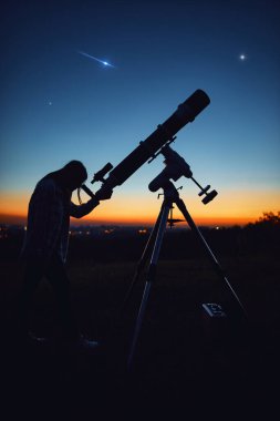 Silhouette of a woman, telescope and countryside under the starry skies.